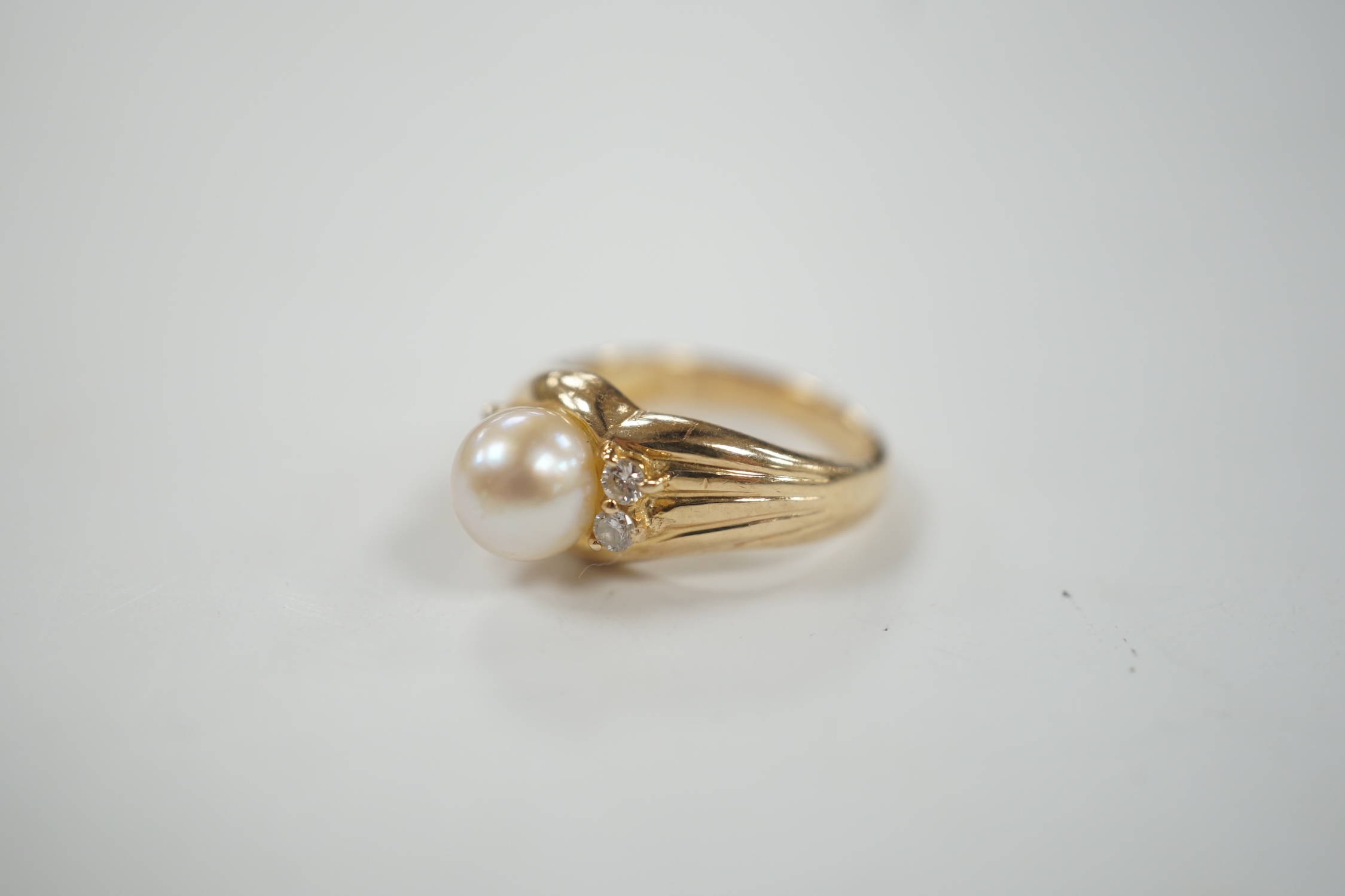 A modern 585 yellow metal, single stone cultured pearl and four stone diamond set ring, size I, gross weight 3.9 grams.